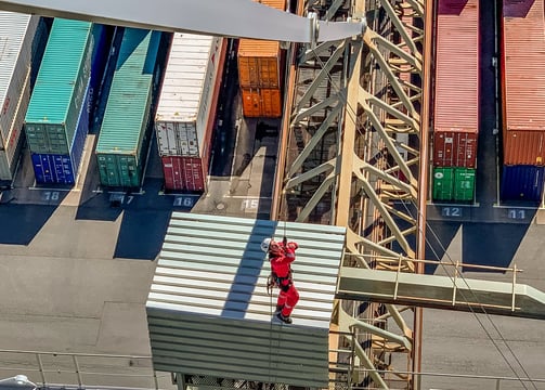 Ein Arbeiter seilt sich von einem Kran im Hafen ab.