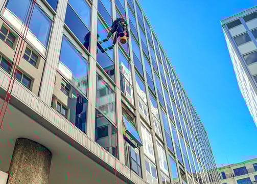 ein mann hängt an einem Seil vor einer Fassade