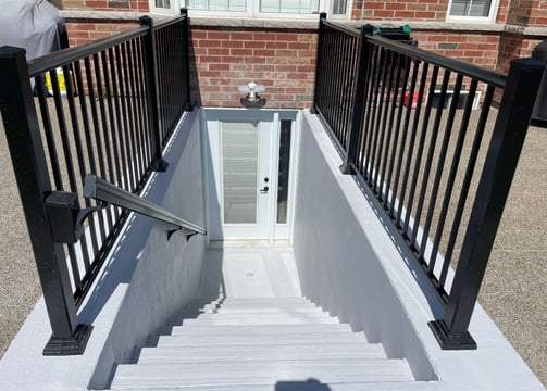 below grade separate entrance with black railings and a glass paned door. Basement finishing.