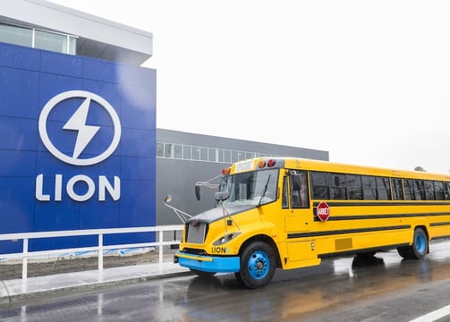 a yellow school bus parked in front of a lion