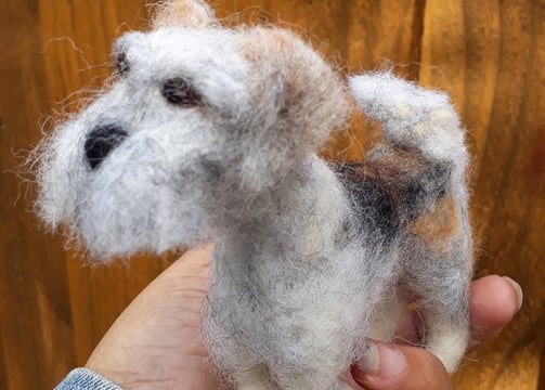 a person holding a small needle felted custom dog