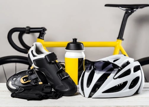 foto raffigurante accessori per bici tra scarpe, casco e borraccia