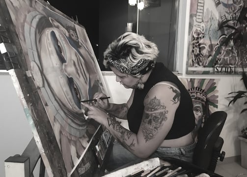 Amanda Amorim no processo de criação de arte usando stencil no estúdio
