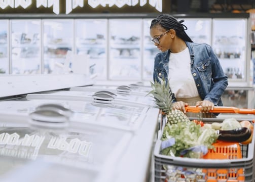 a woman in a denim jacket and jeans standing in a grocery store