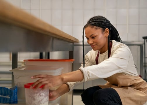 a woman in apron is holding a container of food
