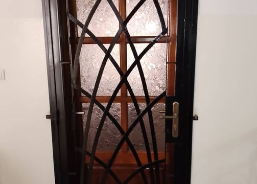 "Porte en métal forgé à motif géométrique, combinant verre texturé et cadre noir