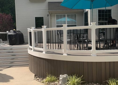 a patio with a new deck remodel and a blue umbrella