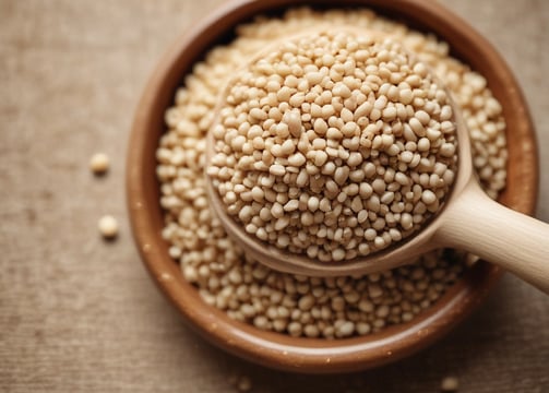 A close-up of peanuts coated in chili powder is placed on a wooden surface. Surrounding these are mounds of coarse salt and chili powder. Lime wedges are arranged in the background, adding a fresh contrast to the scene.