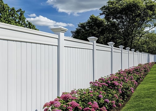 a white vinyl fence with large fence toppers and pink flowers