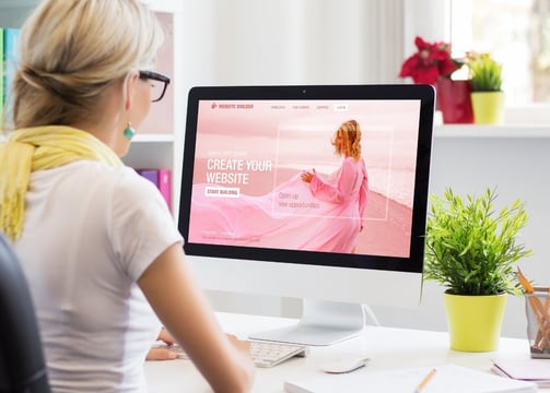 a woman sitting at a desk with a computer screen displaying a websitepage