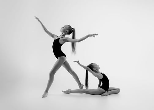 Two gymnasts holding back balance poses during practice.