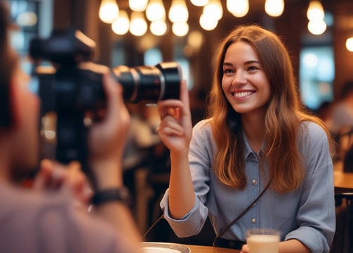A woman stands beside a whiteboard that serves as a weekly planner, organized with days of the week horizontally and different social media platforms vertically. The board is marked with different colored sticky notes labeled with tasks like 'Culture', 'Funny', 'Fun Fact', 'Diversity', and 'Product'. She uses a pen to make a check mark while looking at the board. The layout is colorful and orderly, indicating a planned schedule for social media marketing.