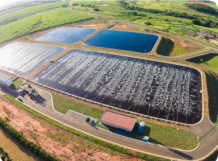 Vista aérea de uma estação de tratamento de esgoto com lagoas de estabilização, cercada por áreas verdes