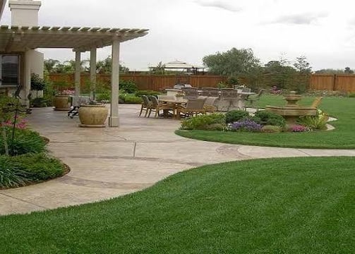 A vibrant garden landscape features lush green and red foliage. In the foreground, there is a structure covered with netting