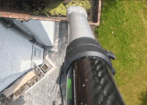 a gutter vacuum being used to clean out the gutters of a two storey house