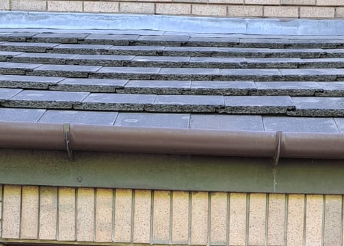 a close-up image of a roof with brown gutter.