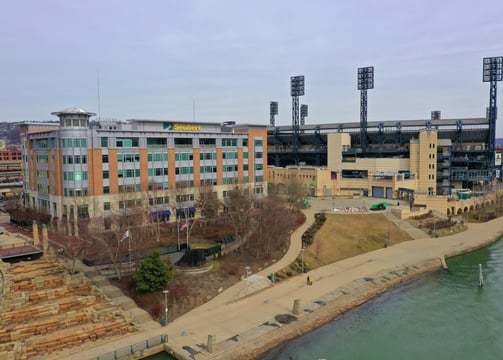 Drone hovering over water, capturing a five-story building with a Seubert sign atop, located on the 