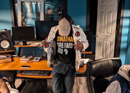 hazema in a baseball cap by a audio recording studio desk