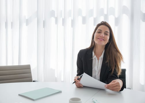 a woman in a suit and tie is smiling and holding a piece of paper