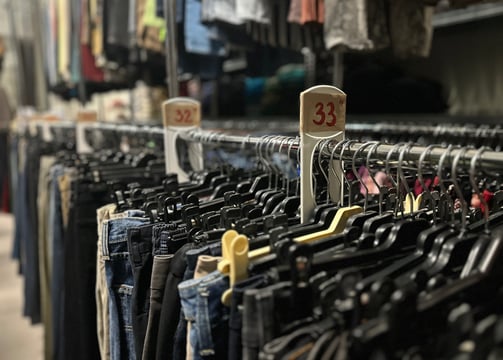 a bunch of clothes hanging on a rack in a warehouse of rental costumes