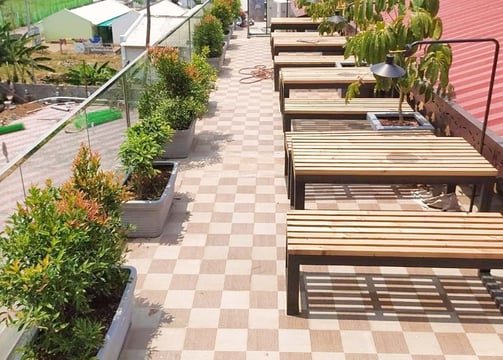 Café landscape with charming seating amidst flowering plants by Garden Designers