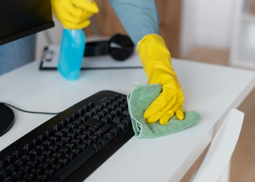 a person cleaning a computer desk with a cloth on it