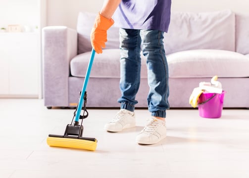 a person cleaning a living room with a broom and a broom