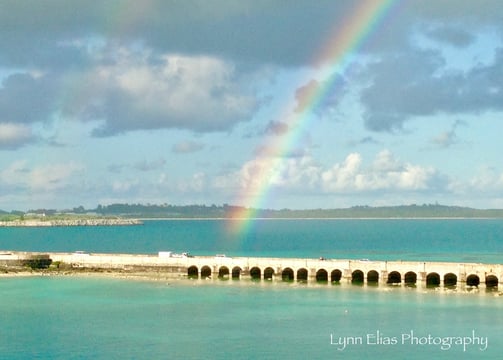 a brightly colored rainbow over a rainbow over the ocean and bridge