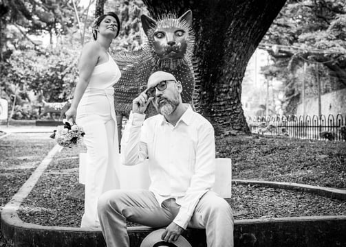 Pareja de novios el dia de su boda, posando junto a una escultura