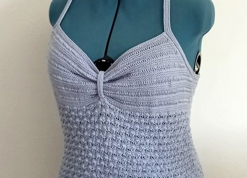 Top d'été tricoté avec un fil coton bleu clair il est posé sur un mannequin de couturière 
