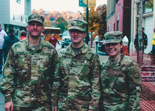 Male and female military in camoflage uniforms standing together in a town plaza