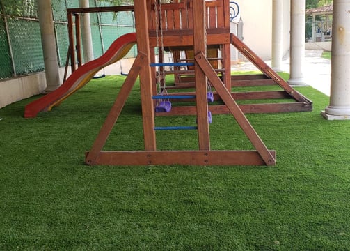 pasto sintetico con juegos infantiles