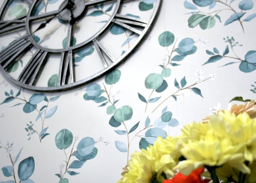 eucalyptus wallpaper with partial silver clock face with yellow flowers below