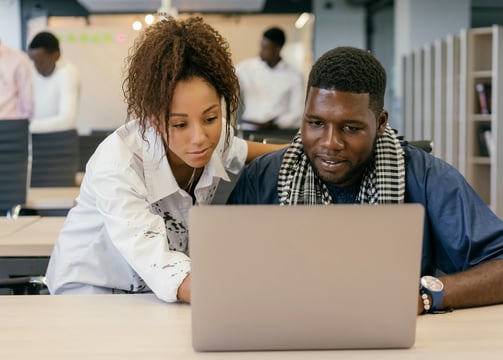 a man and woman looking at a laptop computer