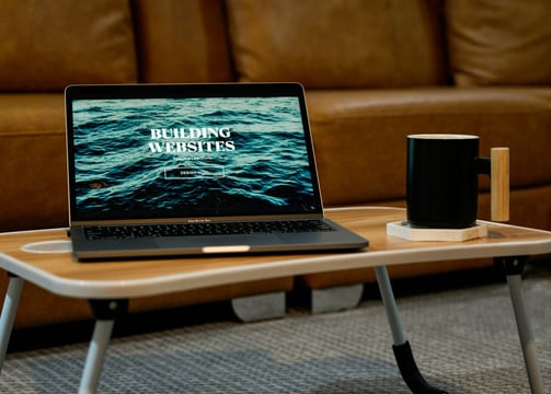 Laptop displaying the words ‘Building Websites’ on the screen, placed on a desk.