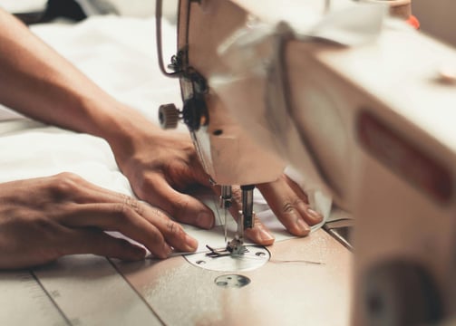 deux mains utilisent une machine à coudre
