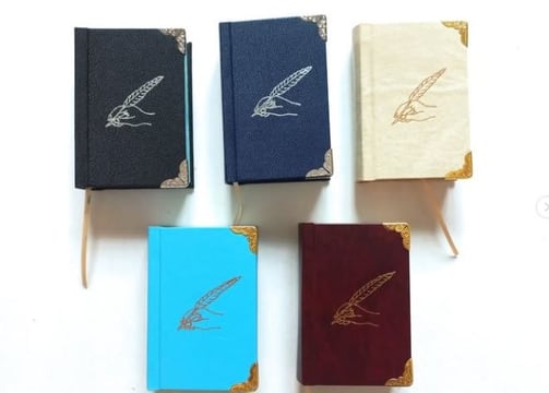 a group of four books with a pen and pencil