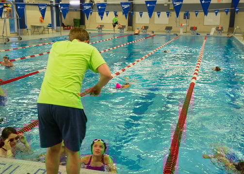Coach demonstrating swimming technique to swimmers