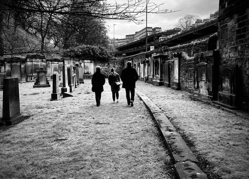 a couple of people walking down a path in a cemetery