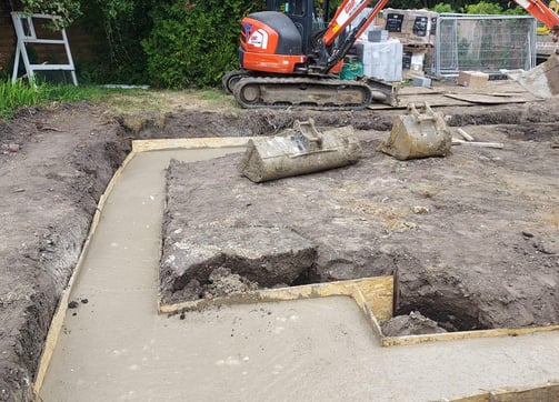 Groundwork contractor laying concrete foundation