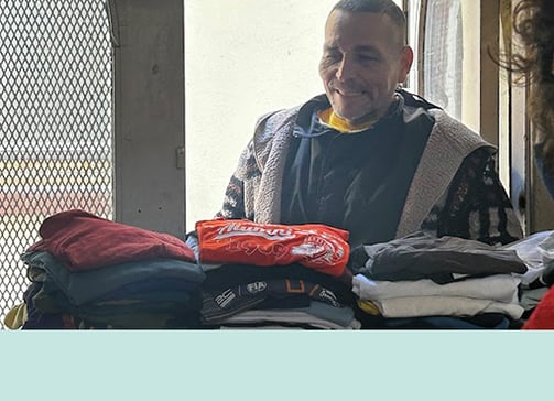 Smiling man about to choose clothes from a donation area