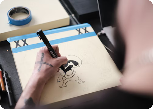 a man is drawing a cartoon character on a notebook