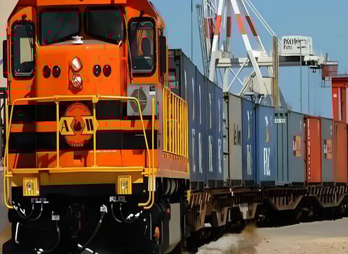 a train with a cargo container crane in the background