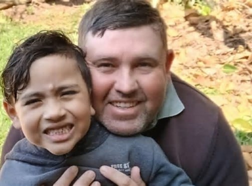 a man and a boy are smiling and hugging