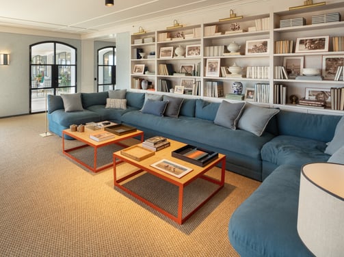 TV lounge at Villa La Gratitud with blue sectional sofa, wall of bookshelves, and large windows.