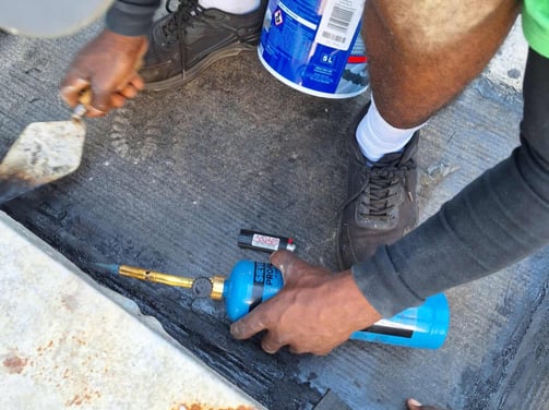 Setting of torch on bitumen with troweling tool, Scottburgh Mall, South Coast, Amanzimtoti
