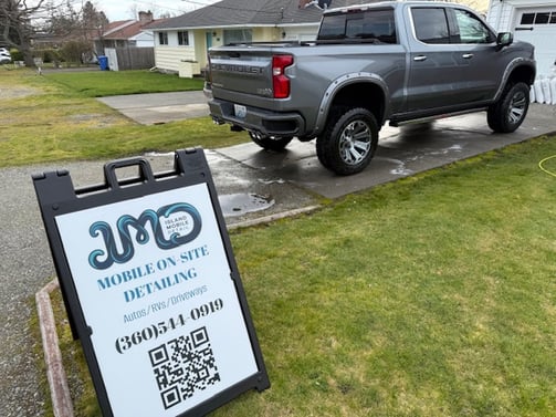 company sign with silver truck and grass