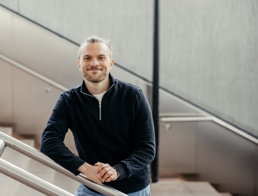 a man in a black jacket and jeans standing on a stair case