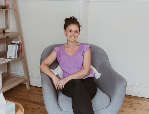 a woman sitting in a chair with a bookcase