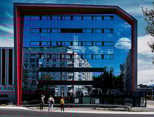 a person walking down a street with a large mirrored building in the background, in Geneva